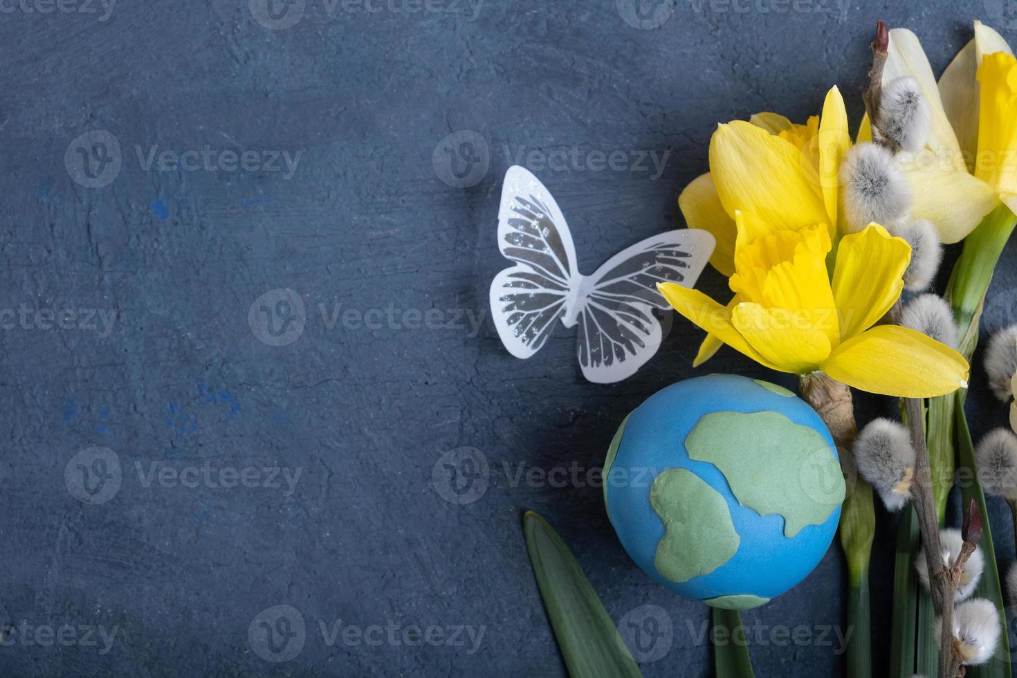 Globe, flowers and butterfly with copy space. Happy Earth day concept flat lay, top view. photo