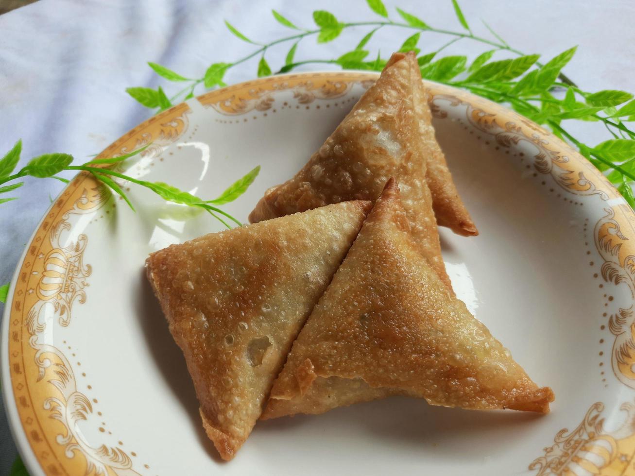 indonesio vegetal sambusa con carne pescado relleno en un mini lámina. un sambusa o samosa es un frito o horneado plato con un sabroso relleno, tal como Unión, carne pez, y otros. tomar imagen desde lado.. foto