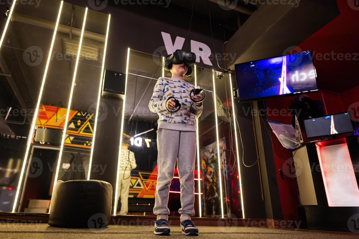 chico niño jugando juego utilizando virtual realidad auriculares y mandos en jugando club. foto