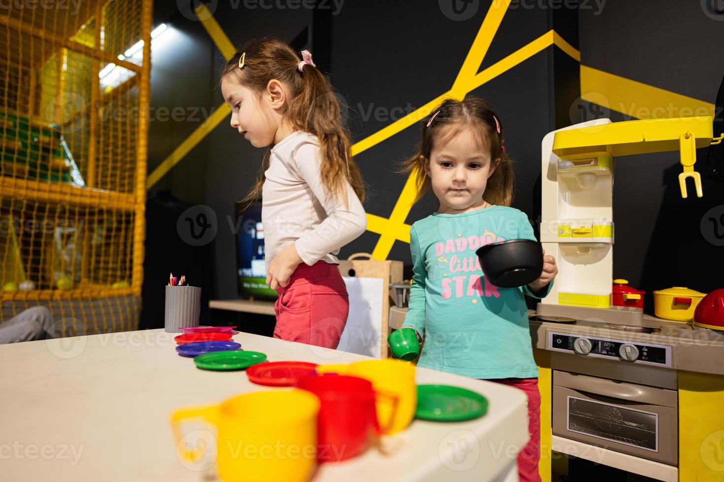 Two sisrers playing in kids kitchen at children play center. photo