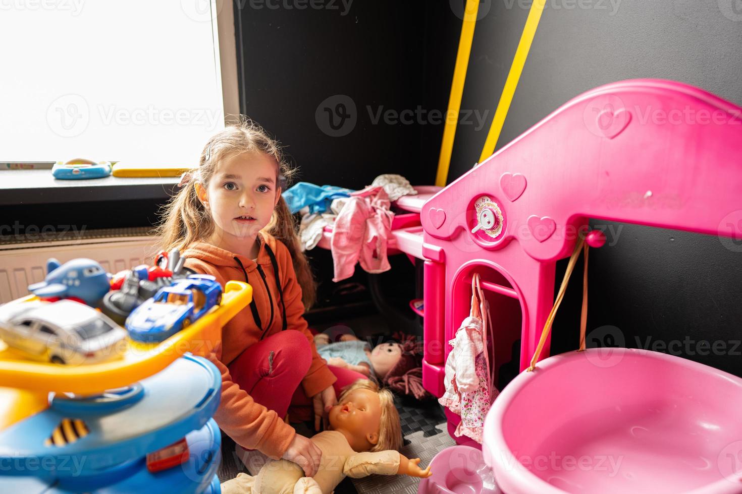 Preschooler girl child in day care center playing with dolls toys. photo