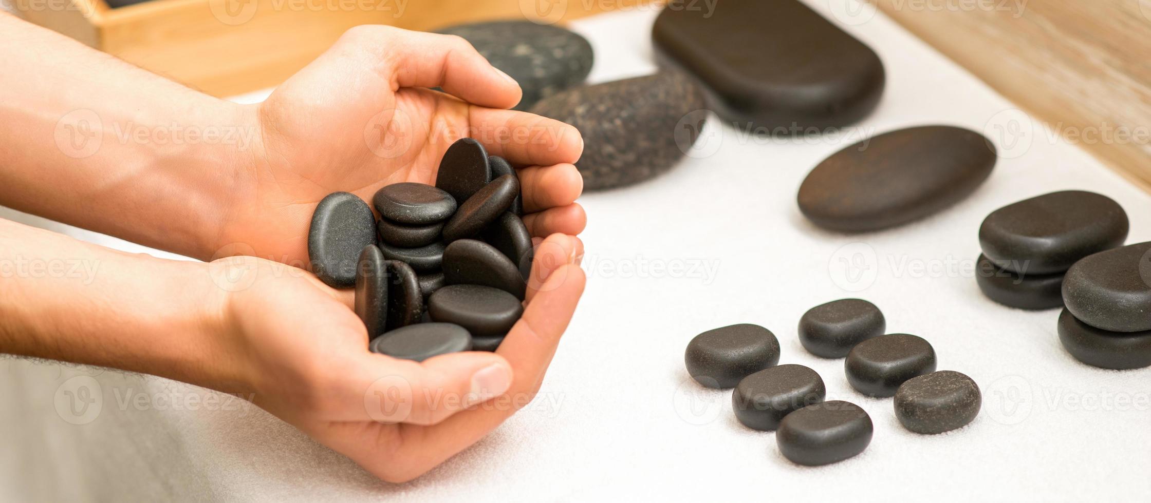 Hands holding spa black pebbles photo