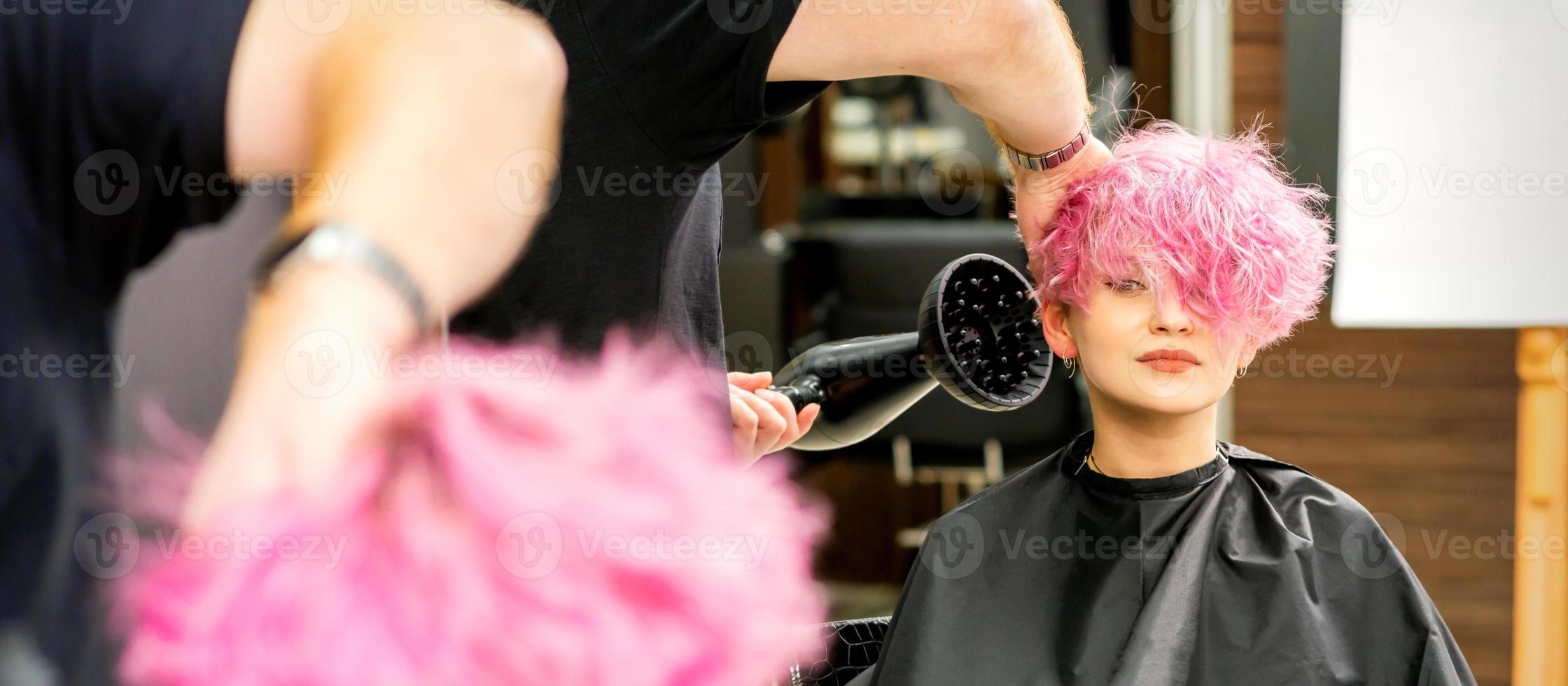 Hairdresser drying pink hair of client photo