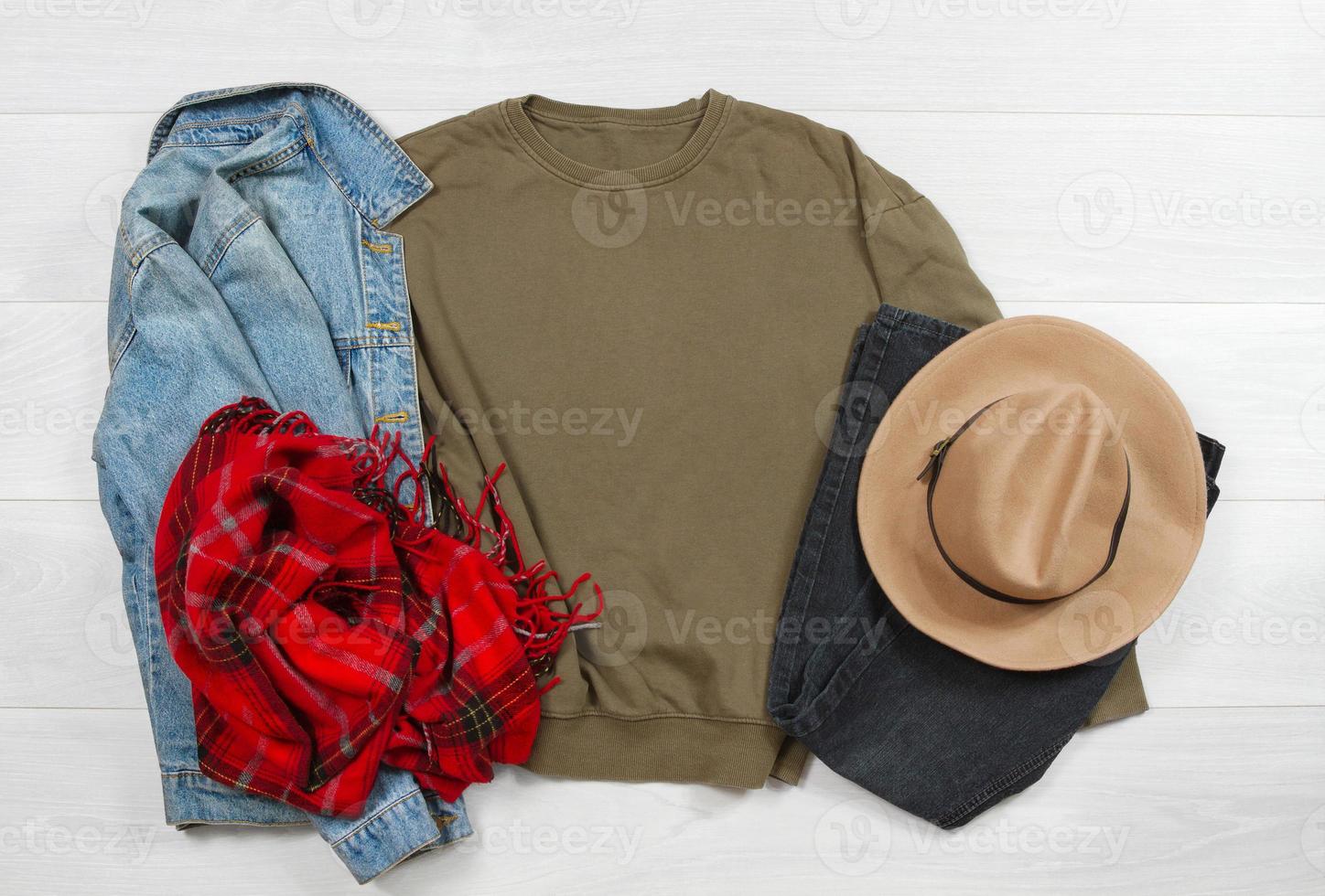 Sweatshirt mockup. Template blank khaki shirt top view on white wooden background. Winter outfit on wood floor. Woman fashion clothes. Spring look of today. Female Jeans, hat, scarf accessories photo