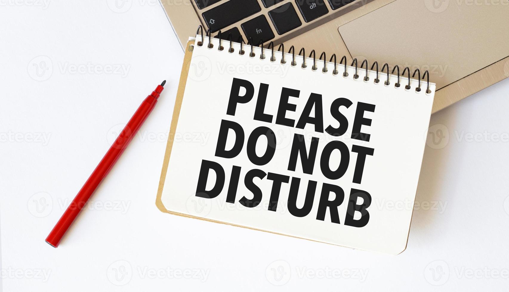 Laptop, red pen and notepad with text please do not disturb in the white background photo