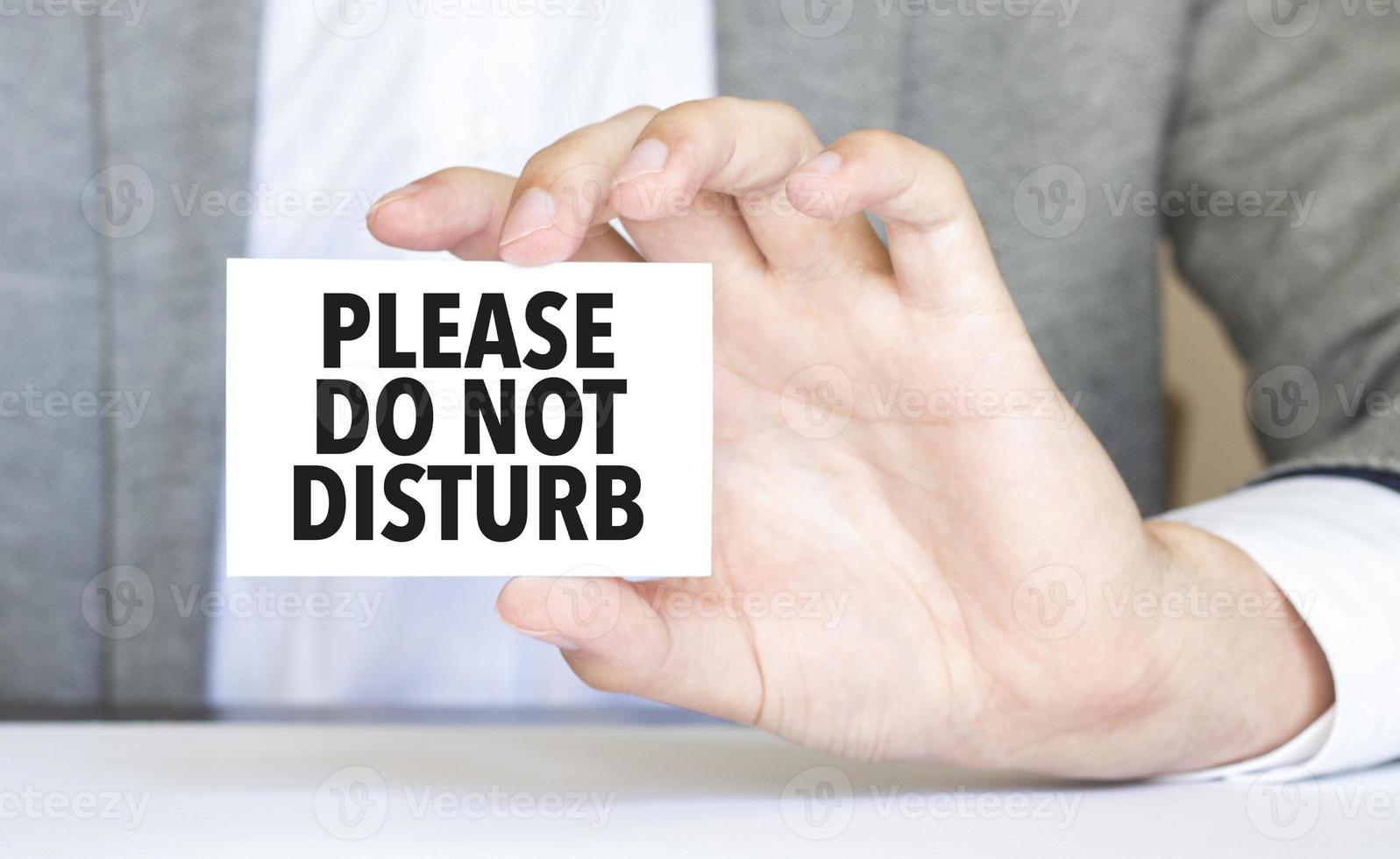 man's hand holding paper sheet with please do not disturb words photo