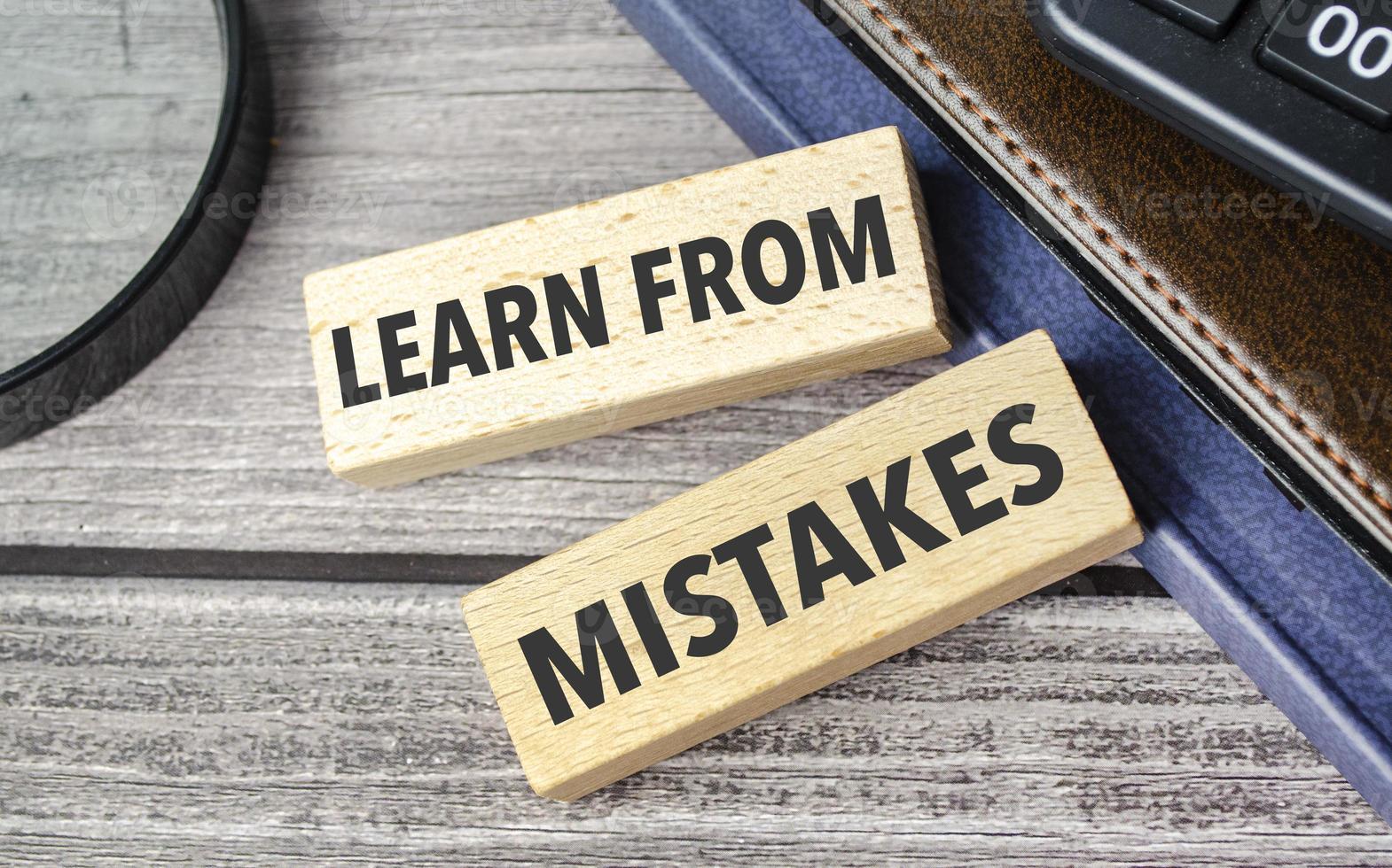 learn from mistakes . text on wooden blocks on wooden background with office supplies photo