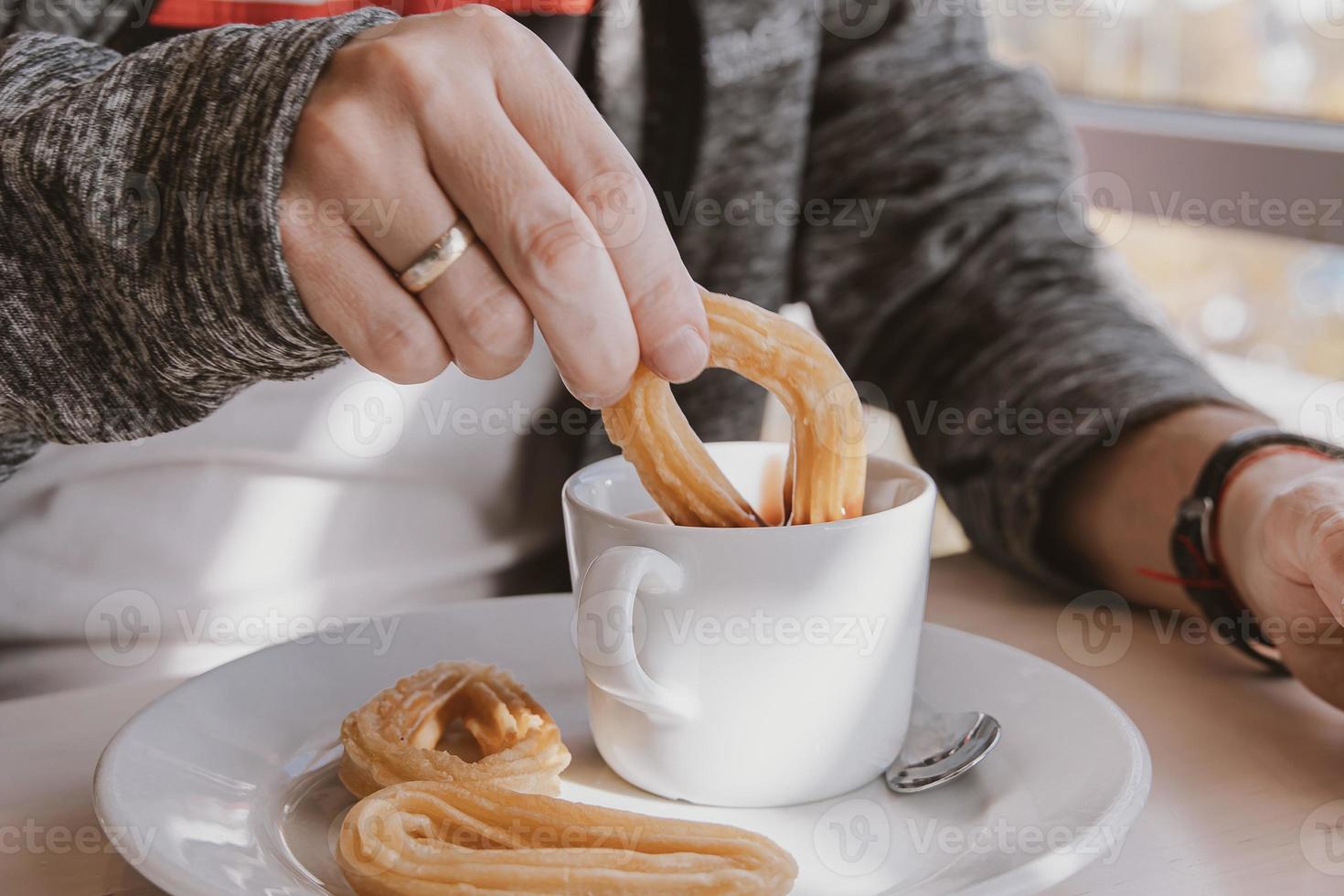 close-up of a man eating a typical  Spanish breakfast and churros with chocolate photo