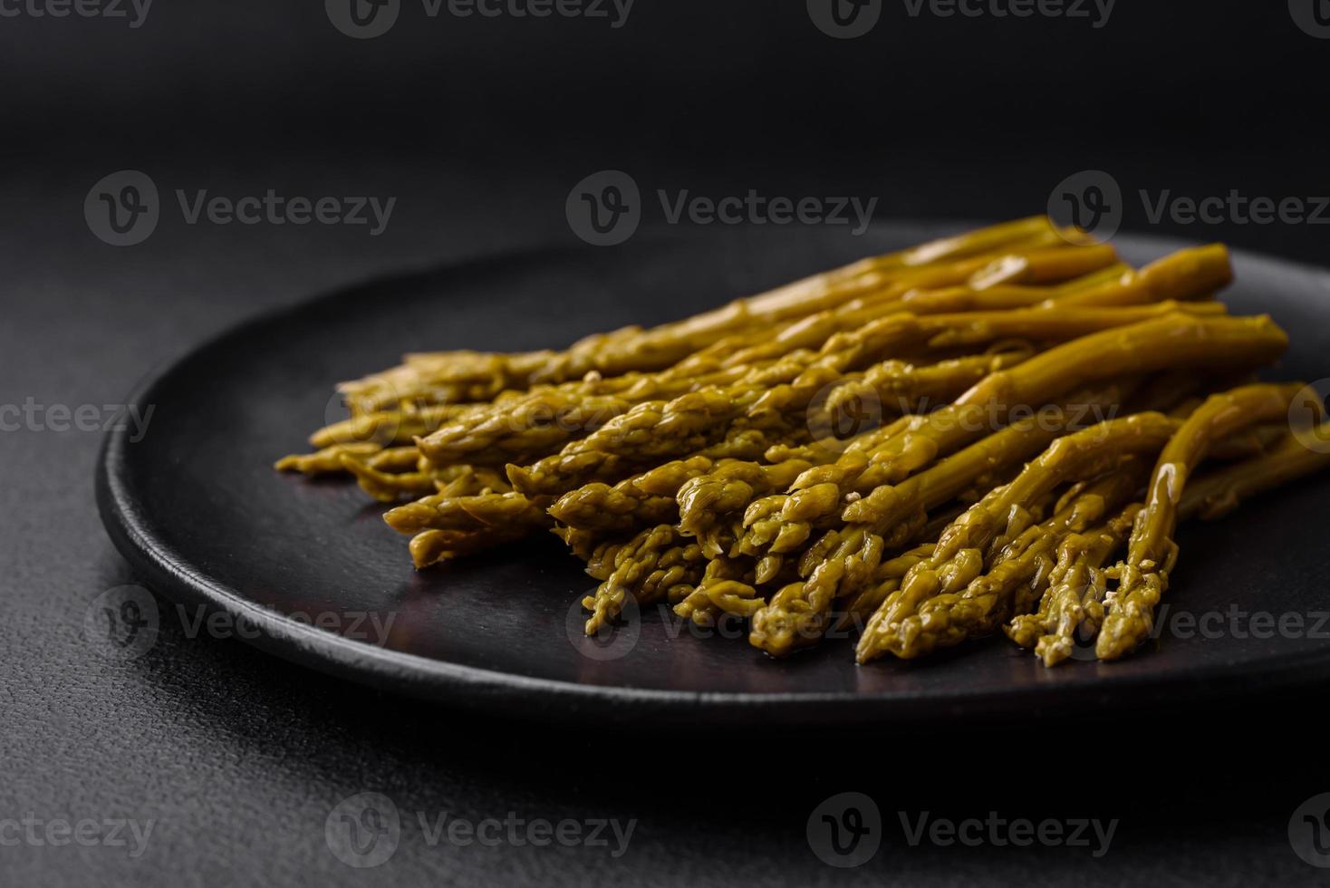 ramitas de delicioso Enlatado espárragos en un negro cerámico plato foto