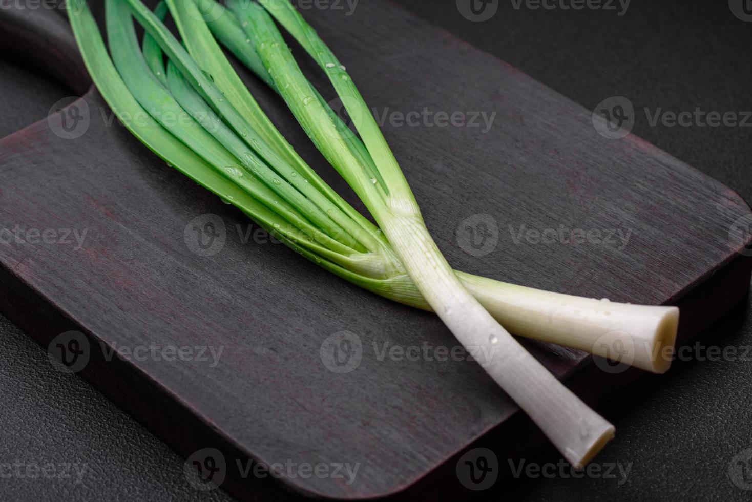 Fresh green onions on a wooden rectangular cutting board photo