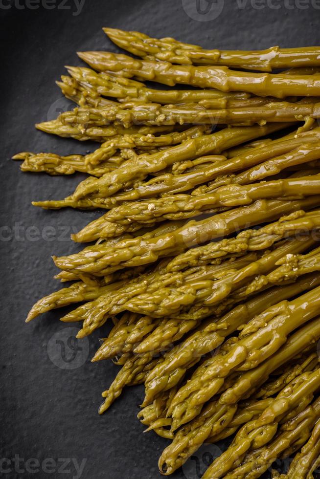 ramitas de delicioso Enlatado espárragos en un negro cerámico plato foto