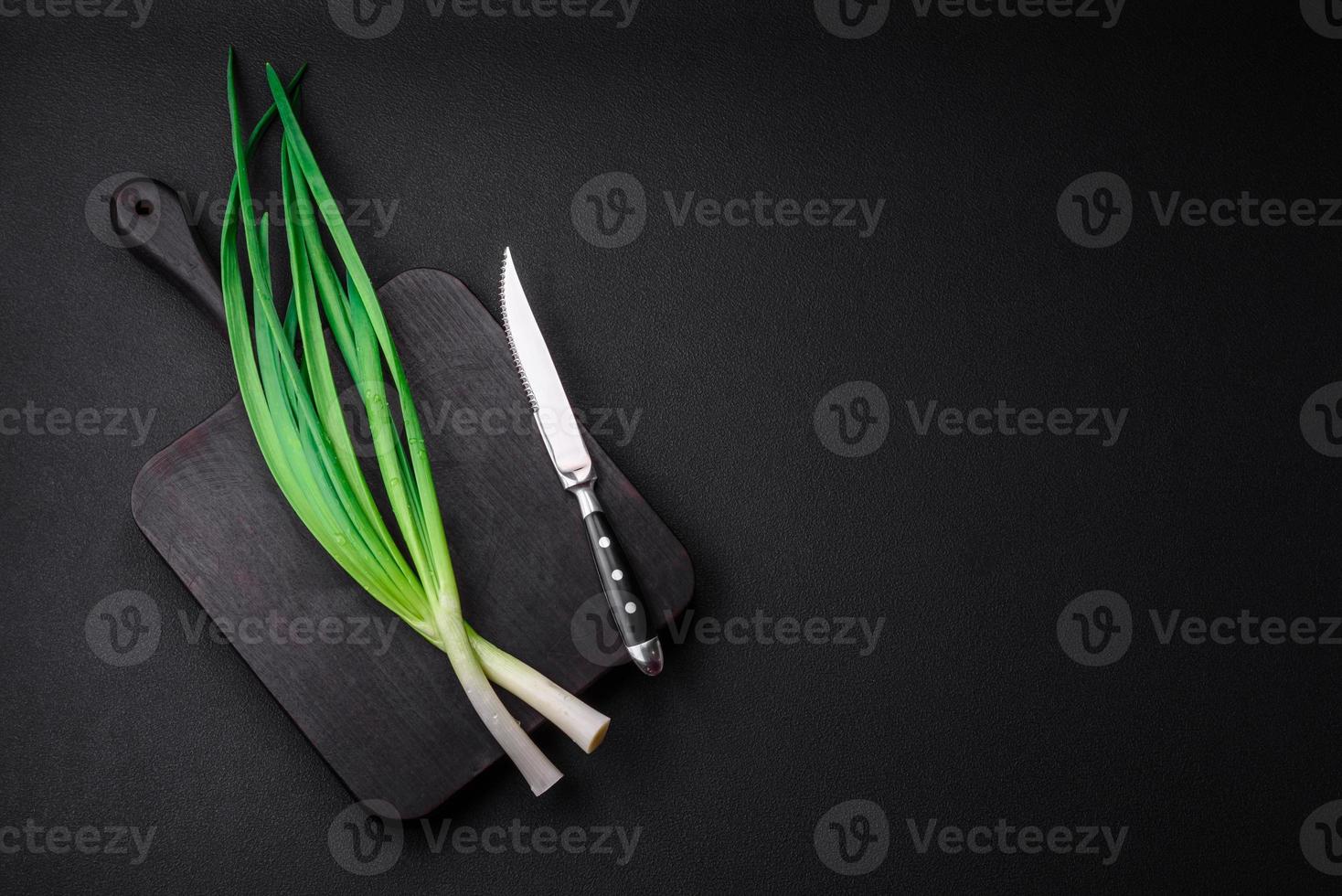 Fresh green onions on a wooden rectangular cutting board photo