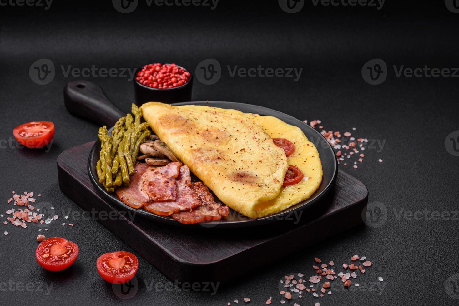 Delicious fresh omelet with cherry tomatoes, bacon, asparagus and spices photo