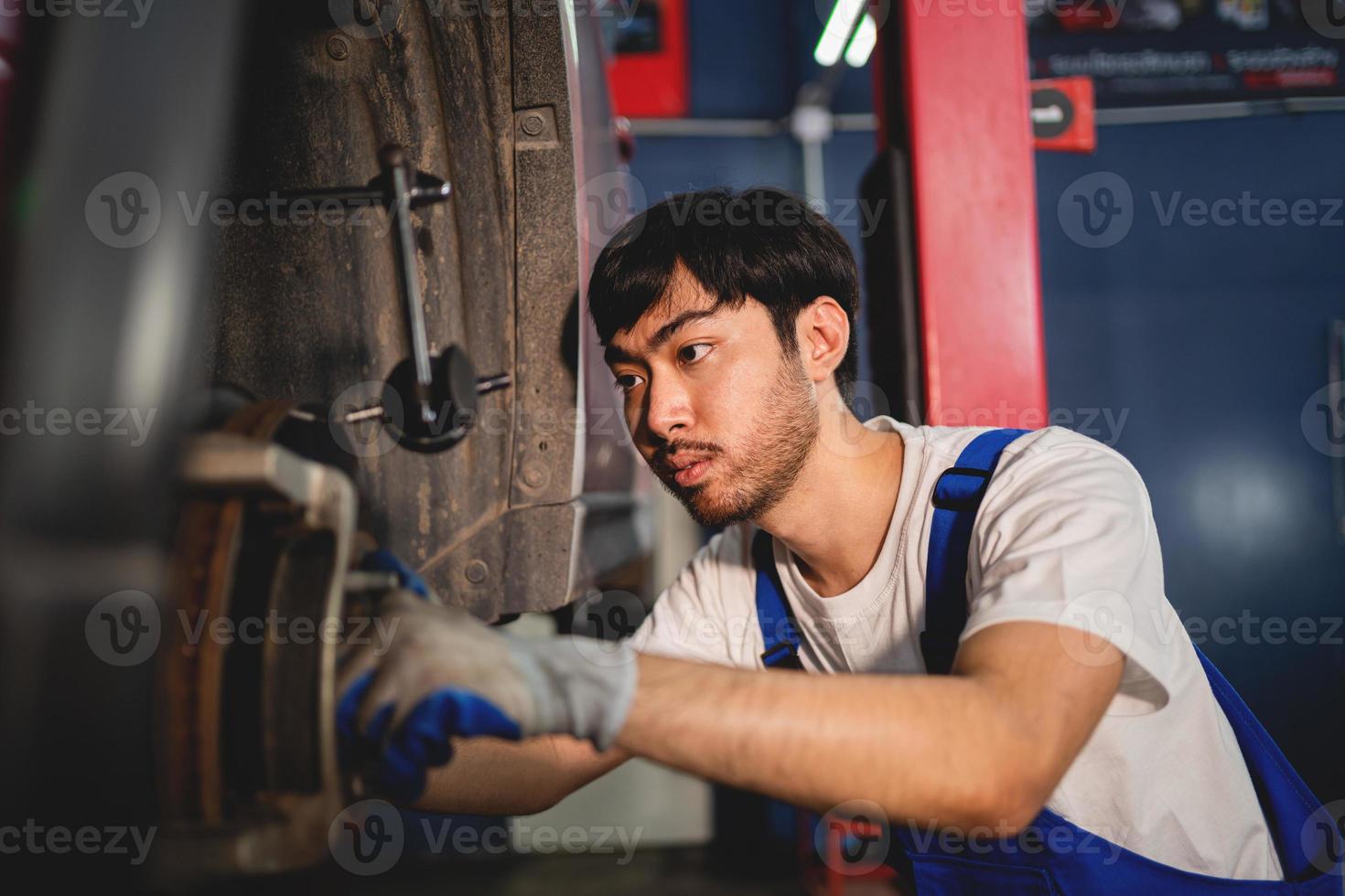 de cerca, auto mecánico reparador utilizando un enchufe llave inglesa trabajando motor reparar en el cochera, cambio de repuesto parte, cheque el kilometraje de el auto, comprobación y mantenimiento Servicio concepto. foto