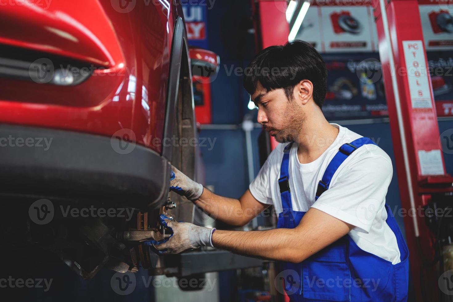 Asian auto mechanic in car garage. Vehicle service personnel are