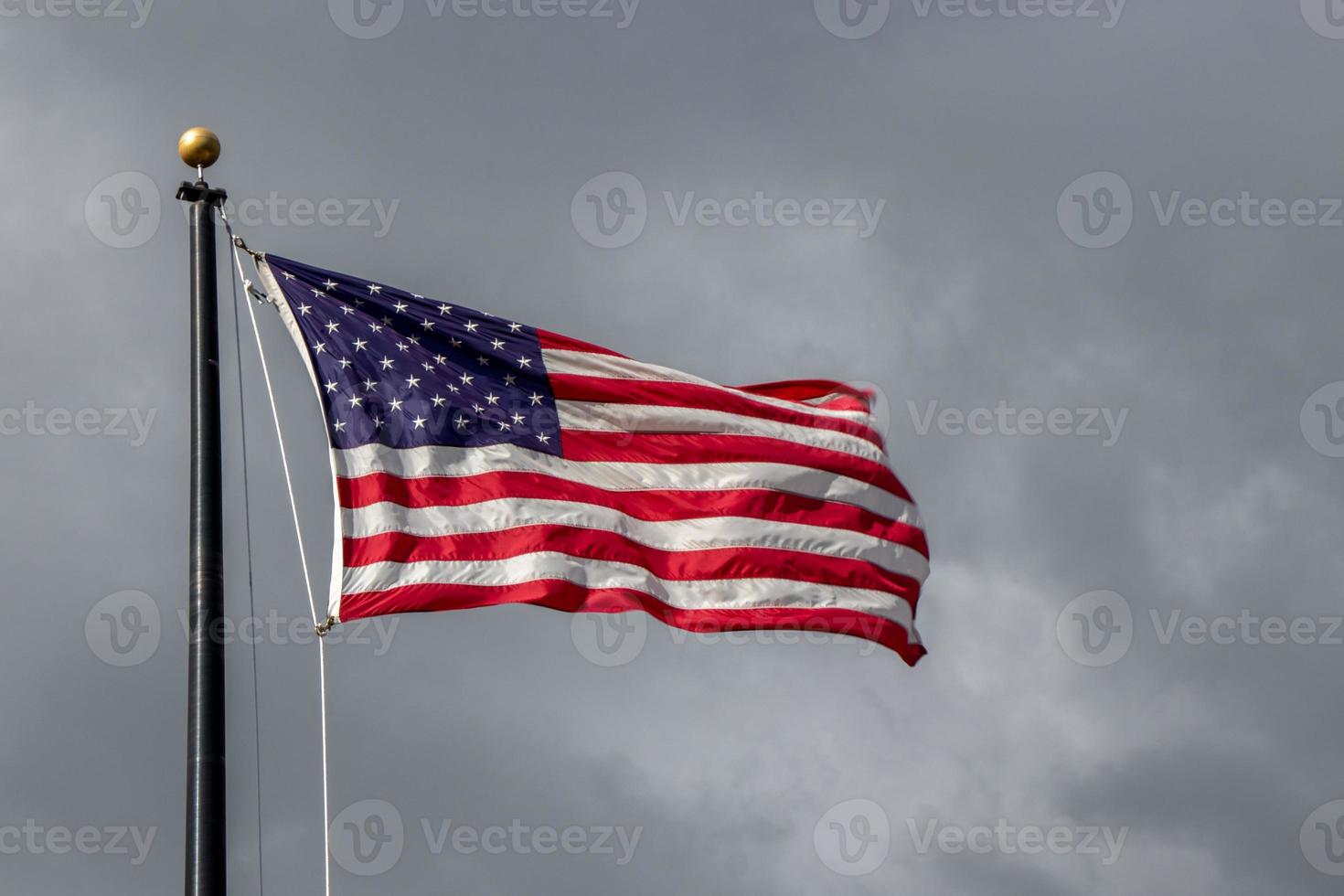 United States flag blowing on the wind with dramatic dark cloudy sky photo