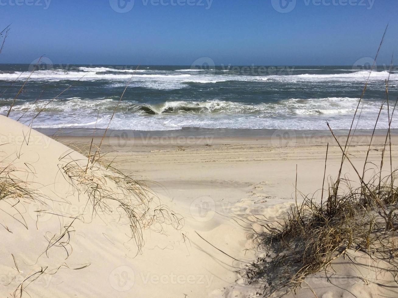 Waves and sand dunes by the sea photo