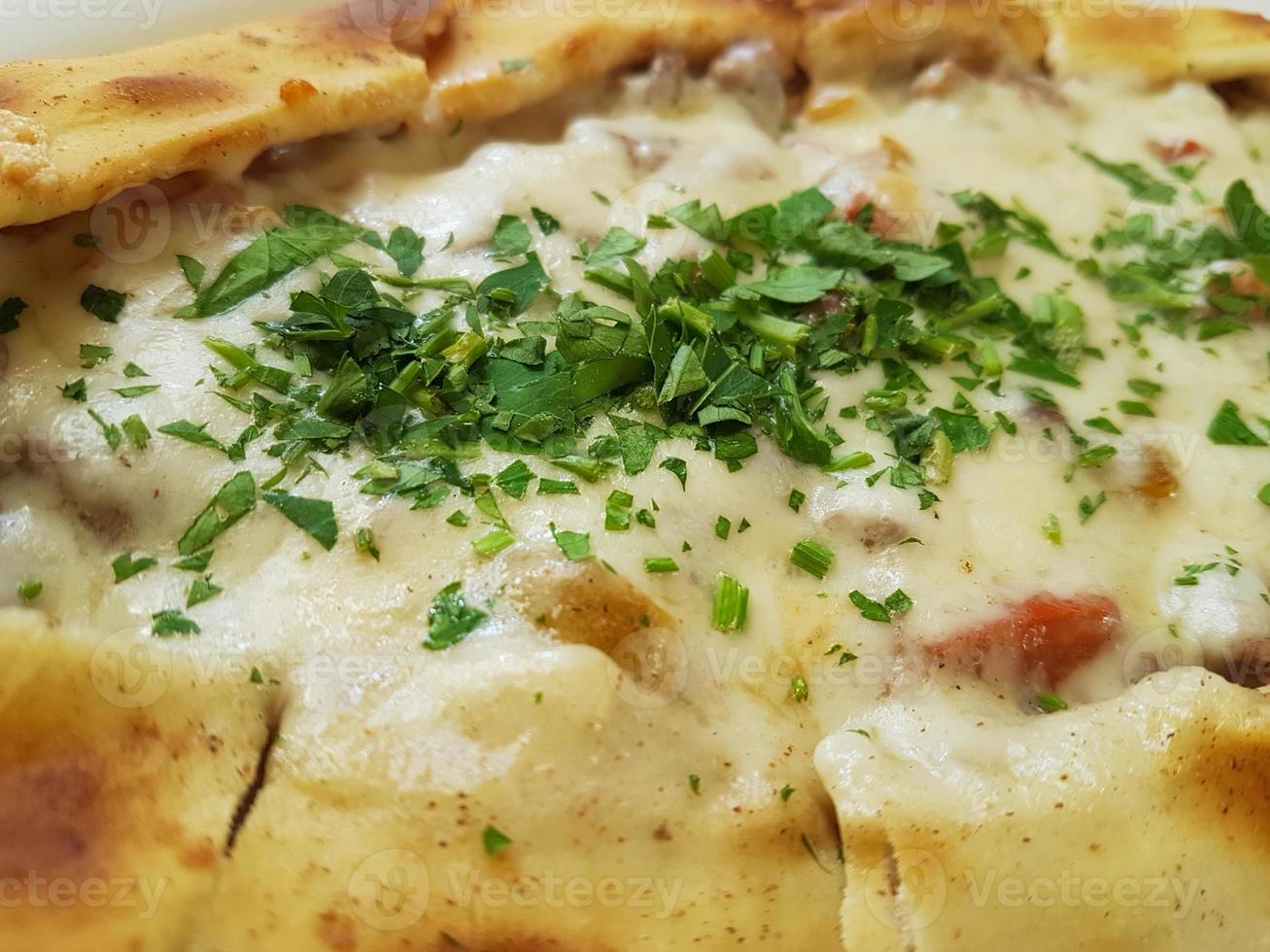 Traditional Turkish Cuisine Kasarli Pide boat-shaped flatbread with cheese, spices and herbs photo