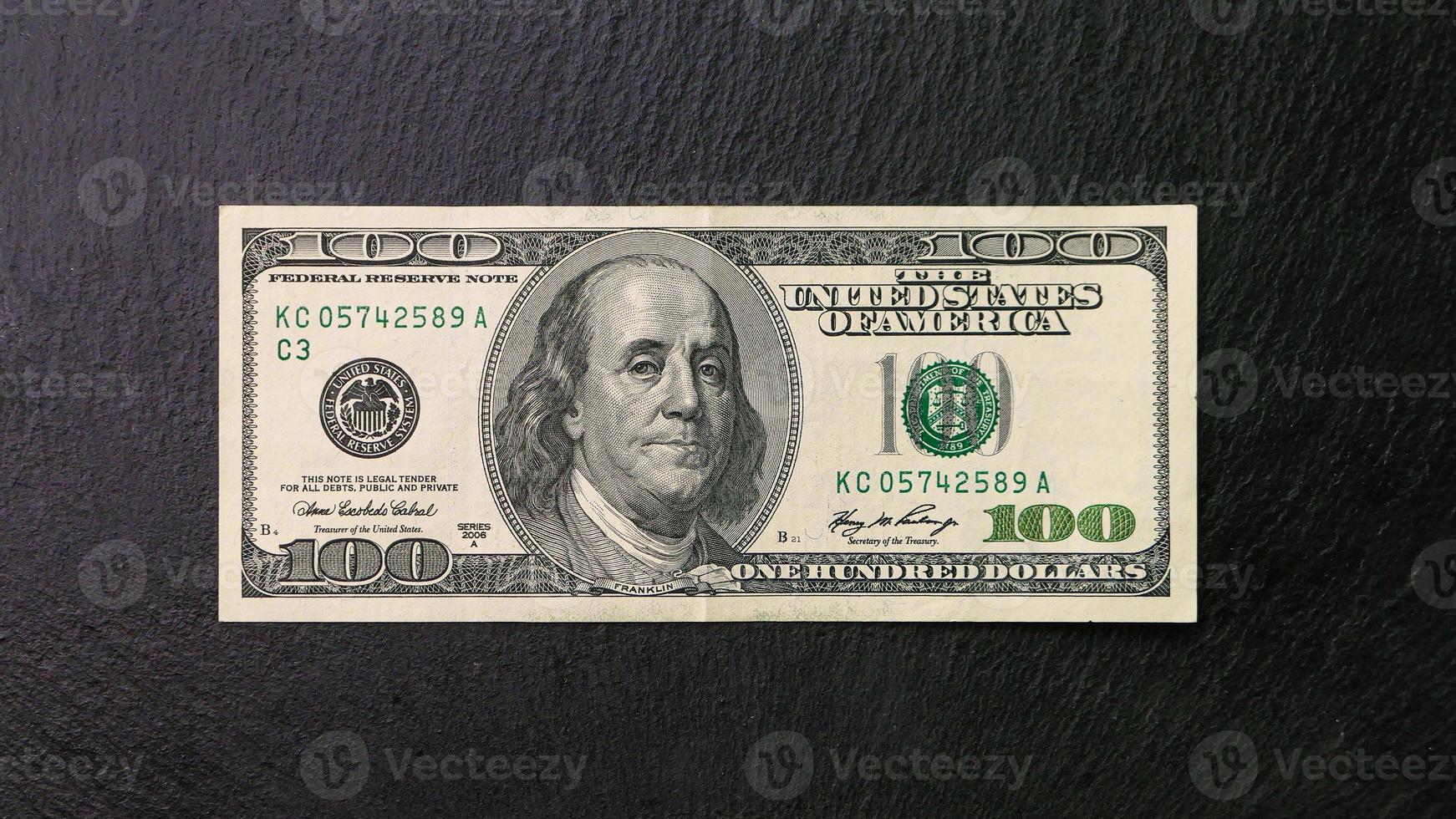 One hundred dollar bill on a black plate Front view Financial concept photo