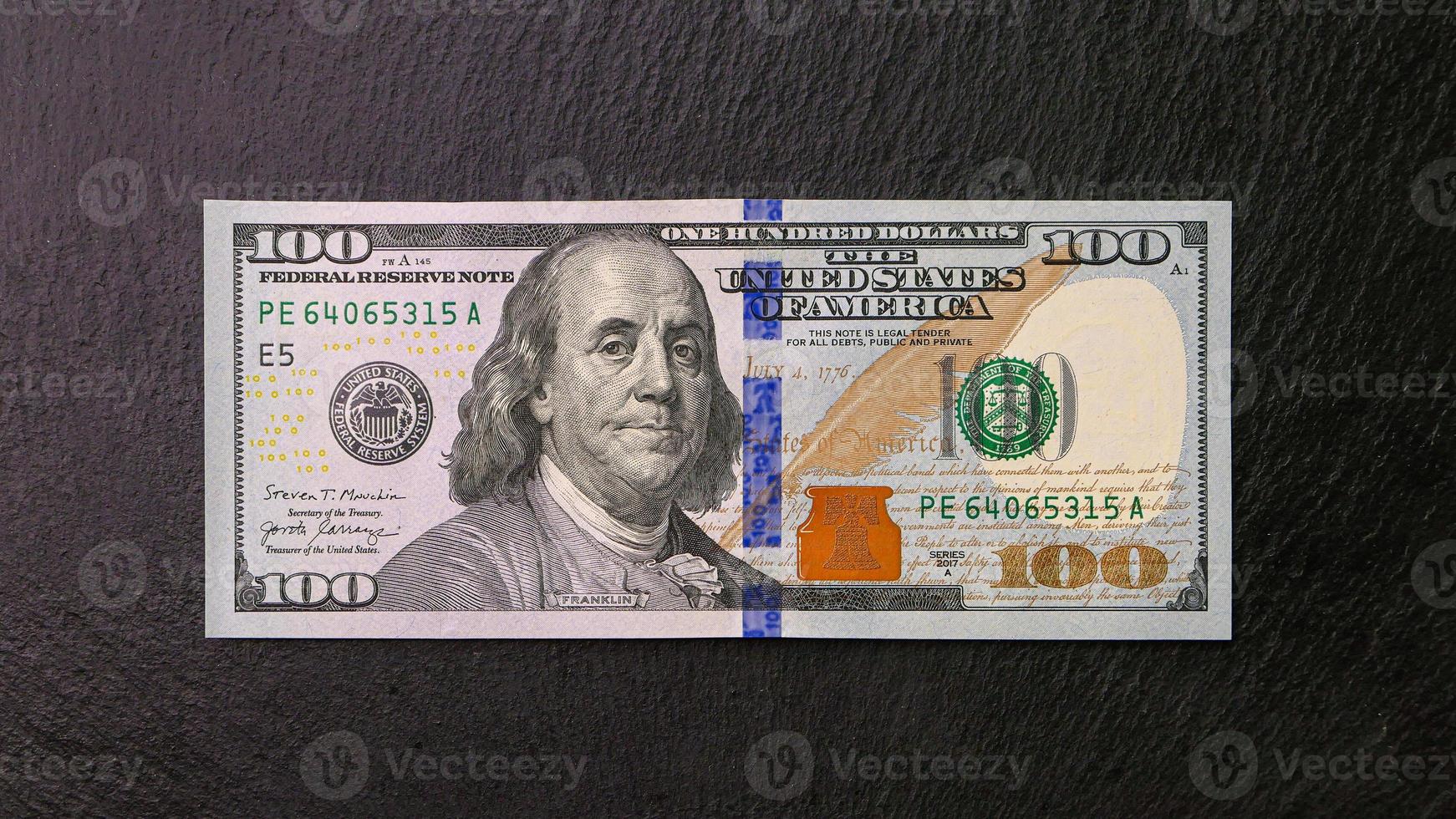 One hundred dollar bill on a black plate Front view Financial concept photo