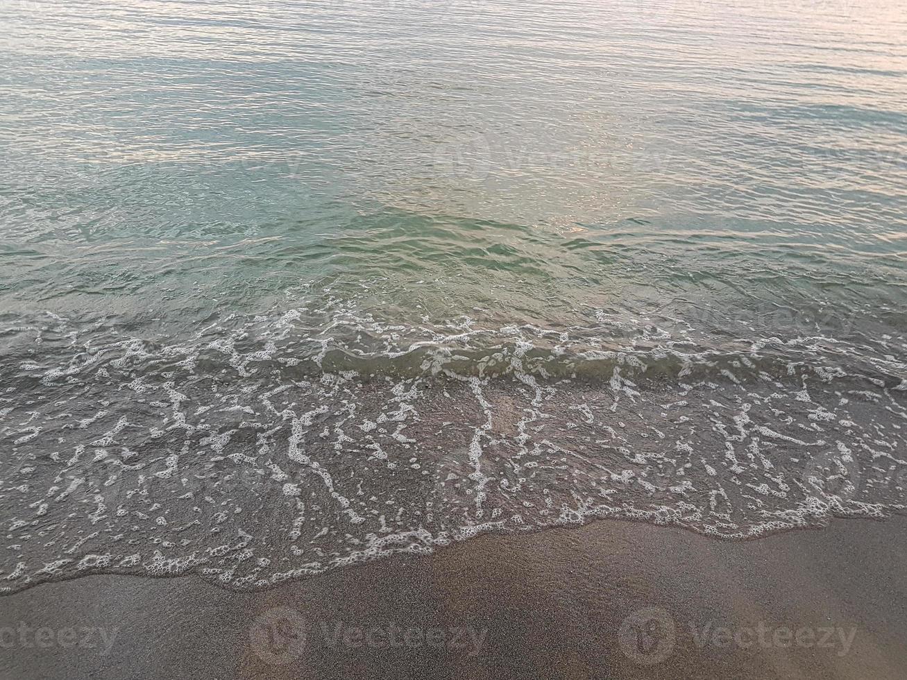 ola del mar en la playa de arena foto