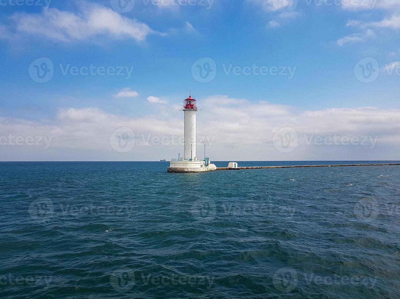 Seascape Sea with lighthouse, calm water and white clouds photo