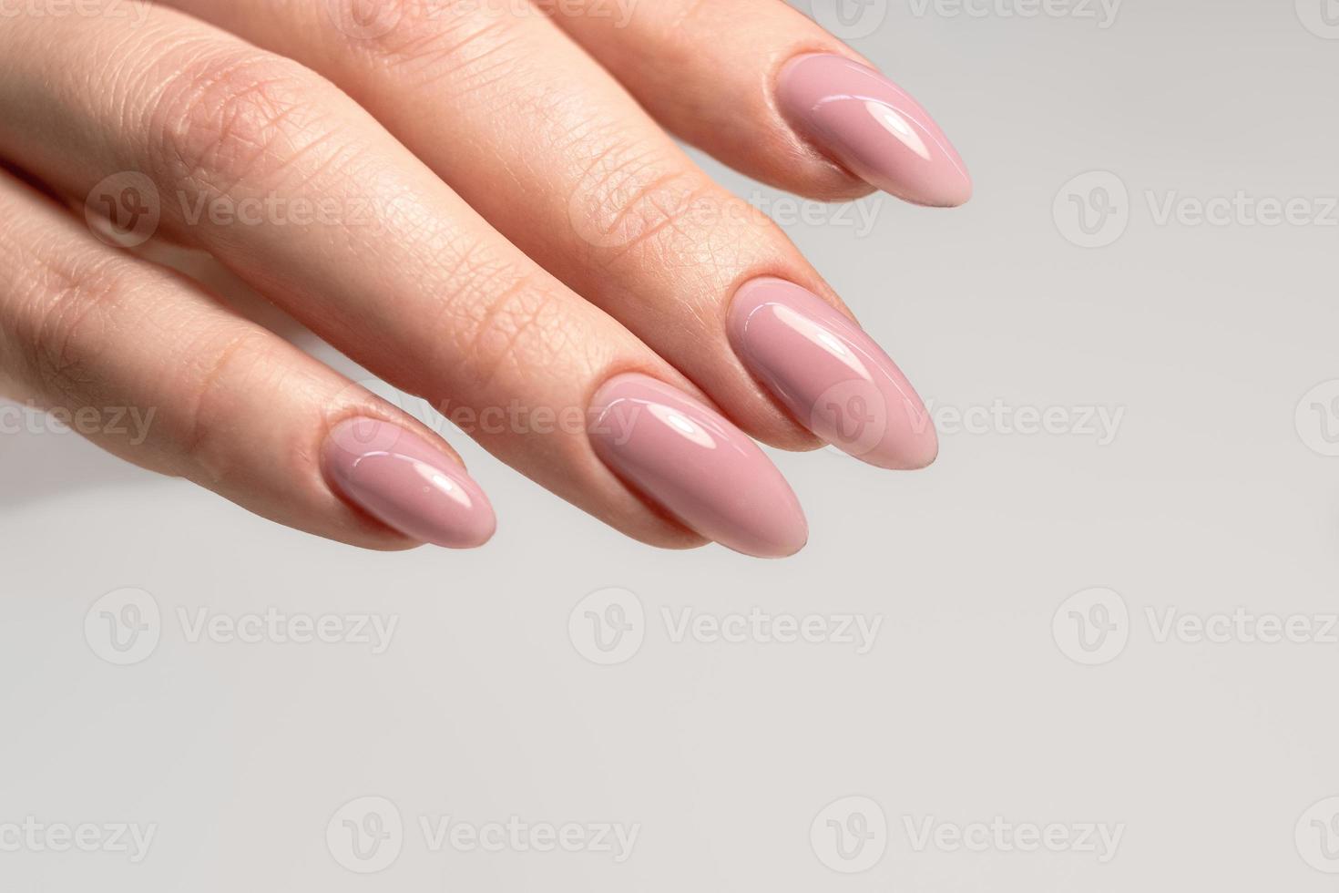 Beautiful manicure with pink nude gel polish. Manicure for women with gel polish. Long nails in the form of almonds. Perfect nude manicure photo