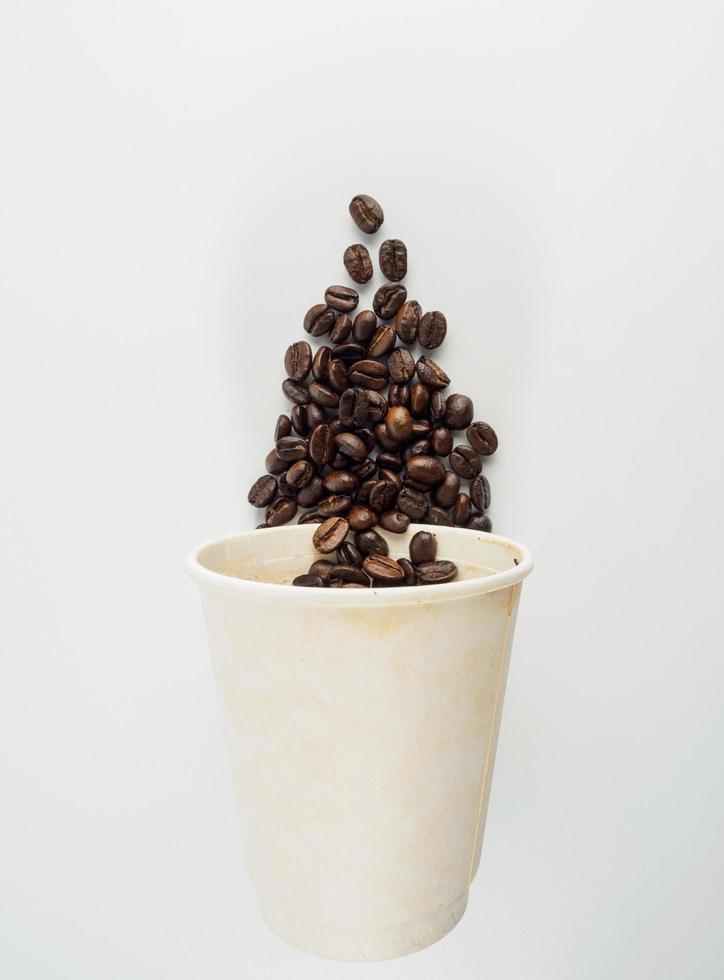 Roasted Arabica coffee beans, ready to make coffee that people like to drink. Placed in a white coffee cup paper on the background. Looks beautiful and appetizing. Drink. photo