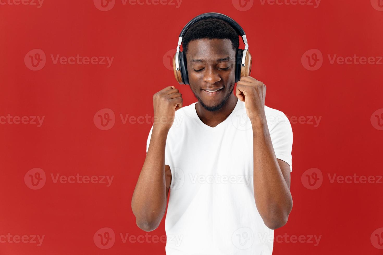 hombre de africano apariencia en blanco camiseta con auriculares escuchando a música divertido foto
