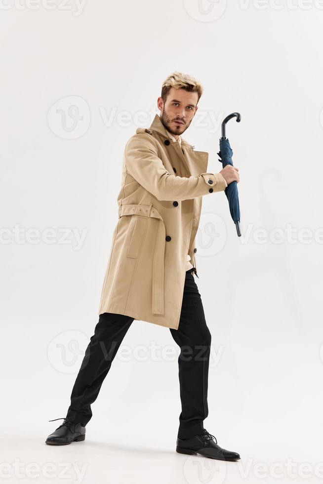 man in a coat umbrella in hands posing modern style autumn clothing photo