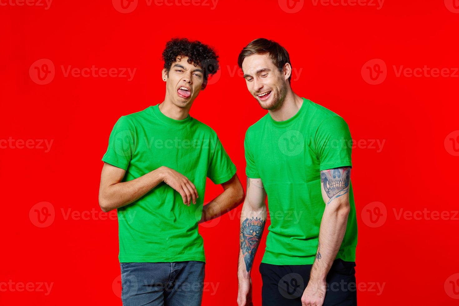 two friends in green t-shirts are standing next to tin with their hands emotions photo