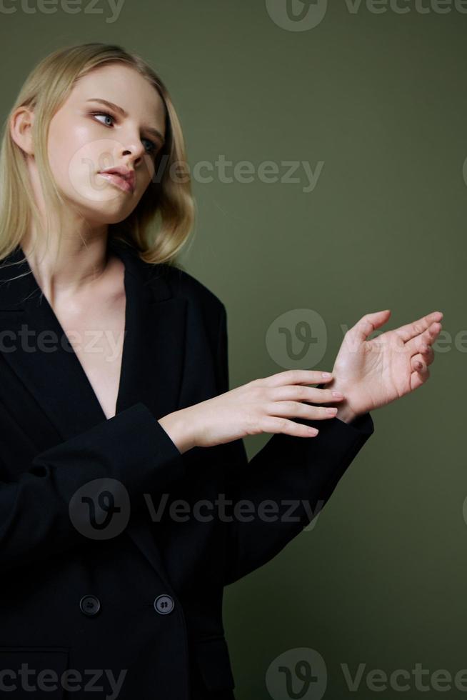 Portrait of a stunning elegant girl in a black suit posing professionally on a green background in the studio. The concept of advertising for designer brands photo