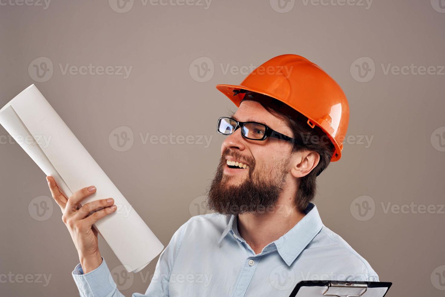 masculino ingeniero con lentes en naranja pintar. profesional planos en manos foto