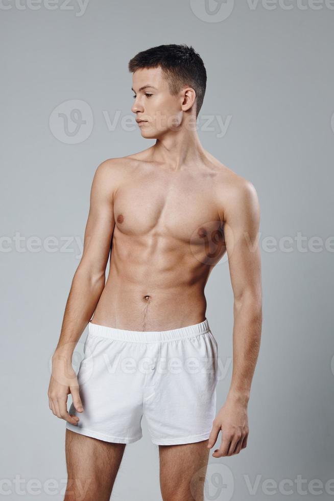 athlete with pumped up abs looking to the side cropped view gray background photo