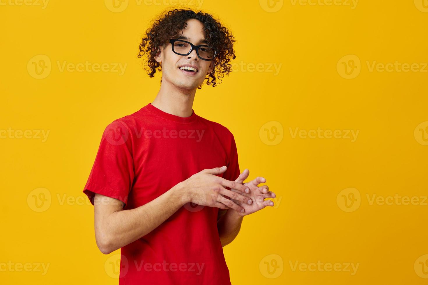 Funny cute myopic young student man in red t-shirt eyewear posing isolated on over yellow studio background. The best offer with free place for advertising. Education College concept photo