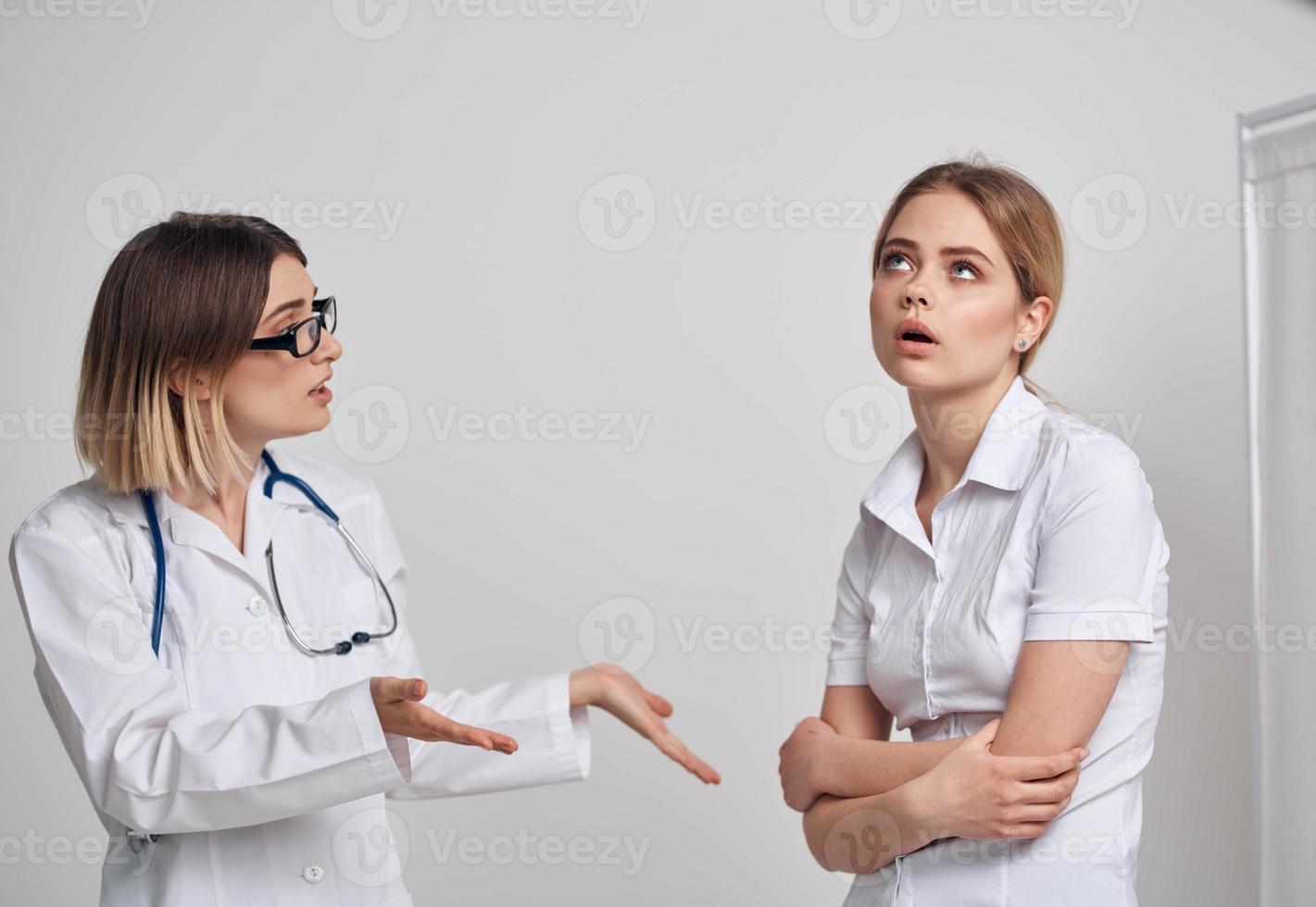 A woman in a T-shirt came to see a doctor in a medical gown photo