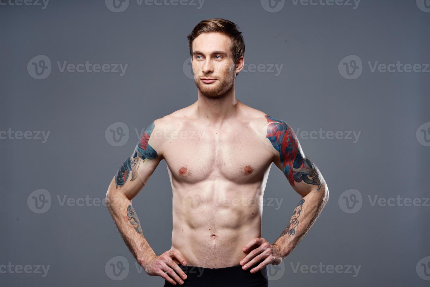 sporty man tattoos on his arms naked torso bodybuilder gray background photo