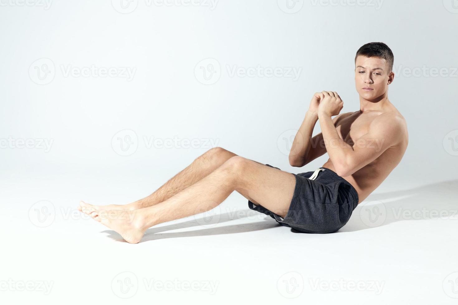 a man shakes the press In a bright room sitting on the floor in full growth on a light background photo