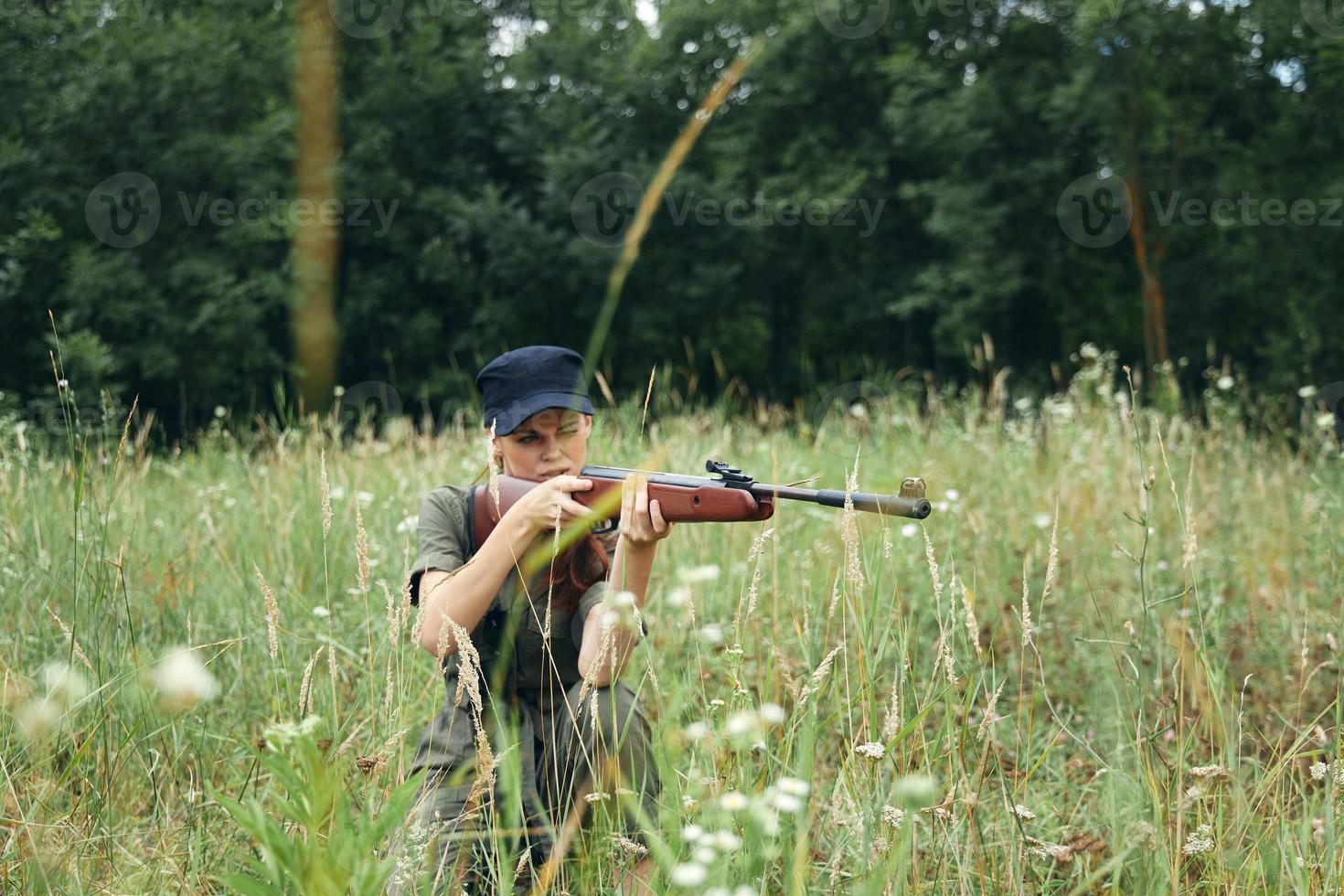 Woman woman aiming aside while sitting on the ground on nature weapons green trees photo