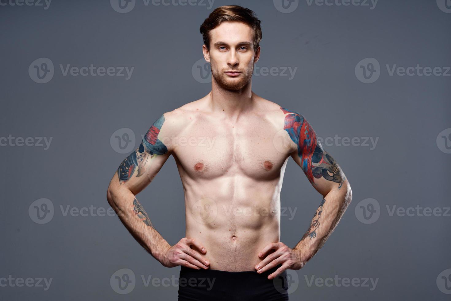 sporty man tattoos on his arms naked torso bodybuilder gray background photo
