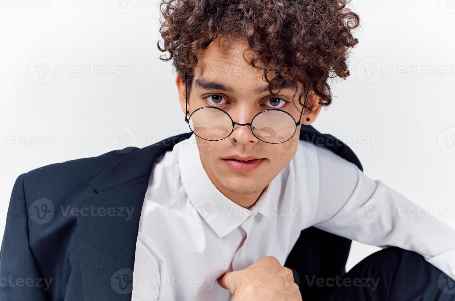 de cerca retrato de hermoso chico con Rizado pelo vistiendo lentes y en un clásico traje foto