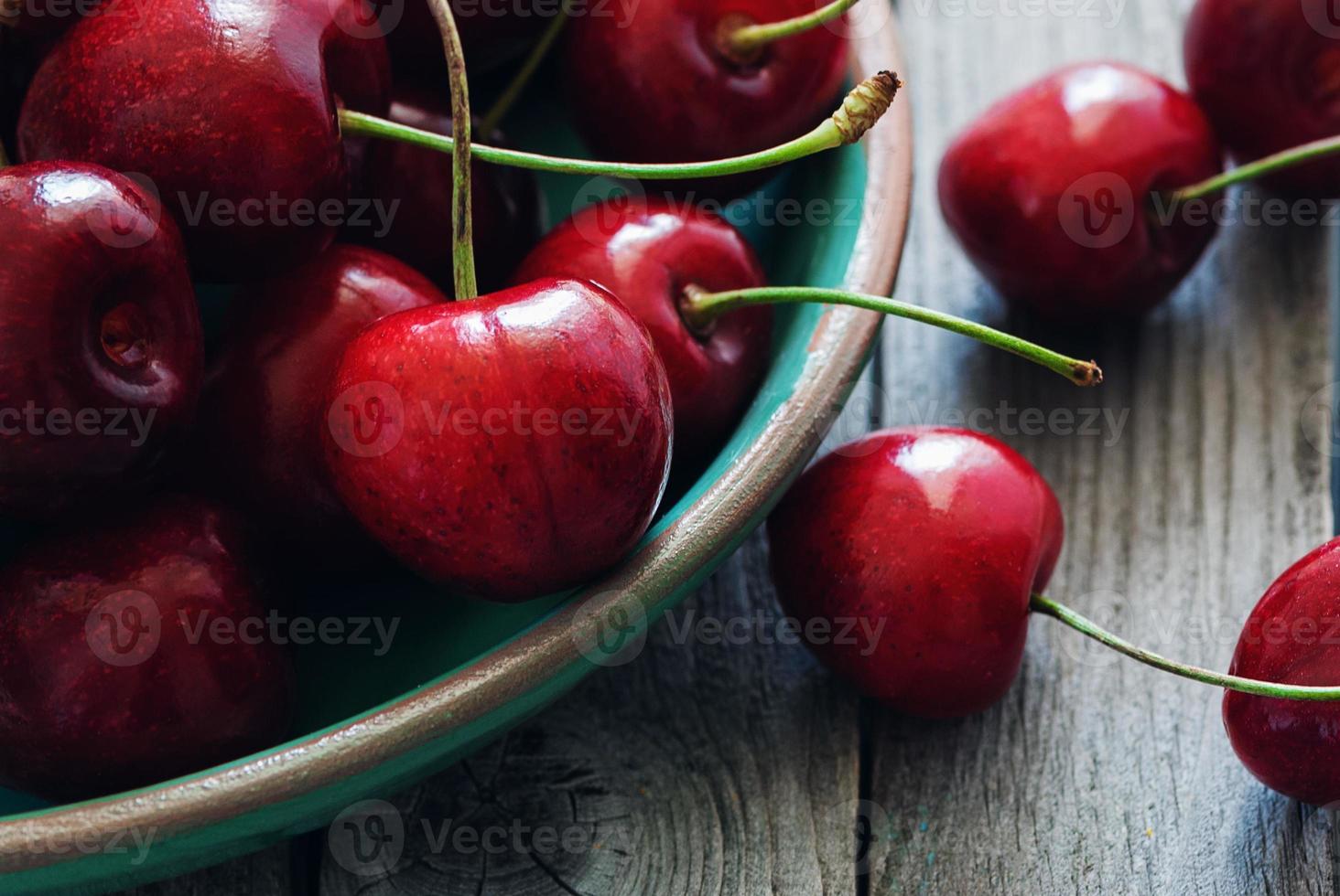 cherries in a bowl on wooden table closeup photo