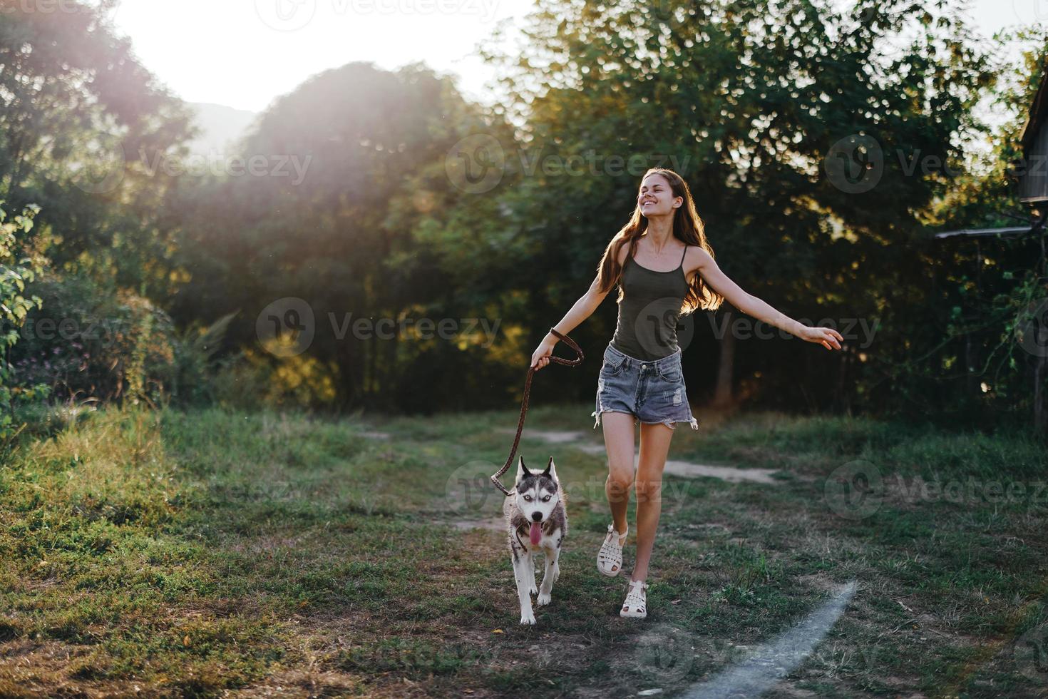 A woman runs with a dog in the forest during an evening walk in the forest at sunset in autumn. Lifestyle sports training with your beloved dog photo