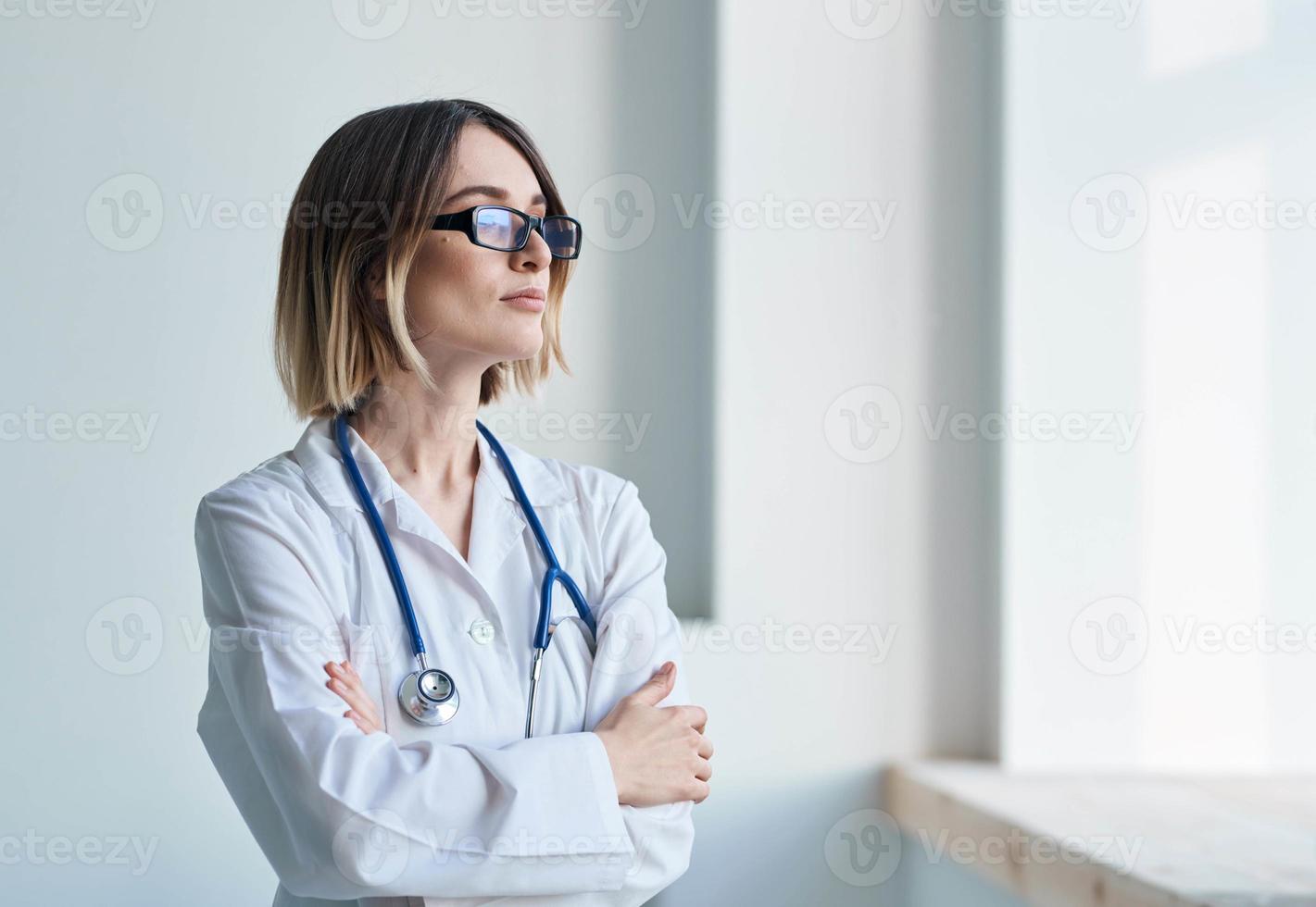profesional médico mujer con lentes cerca ventana y estetoscopio foto