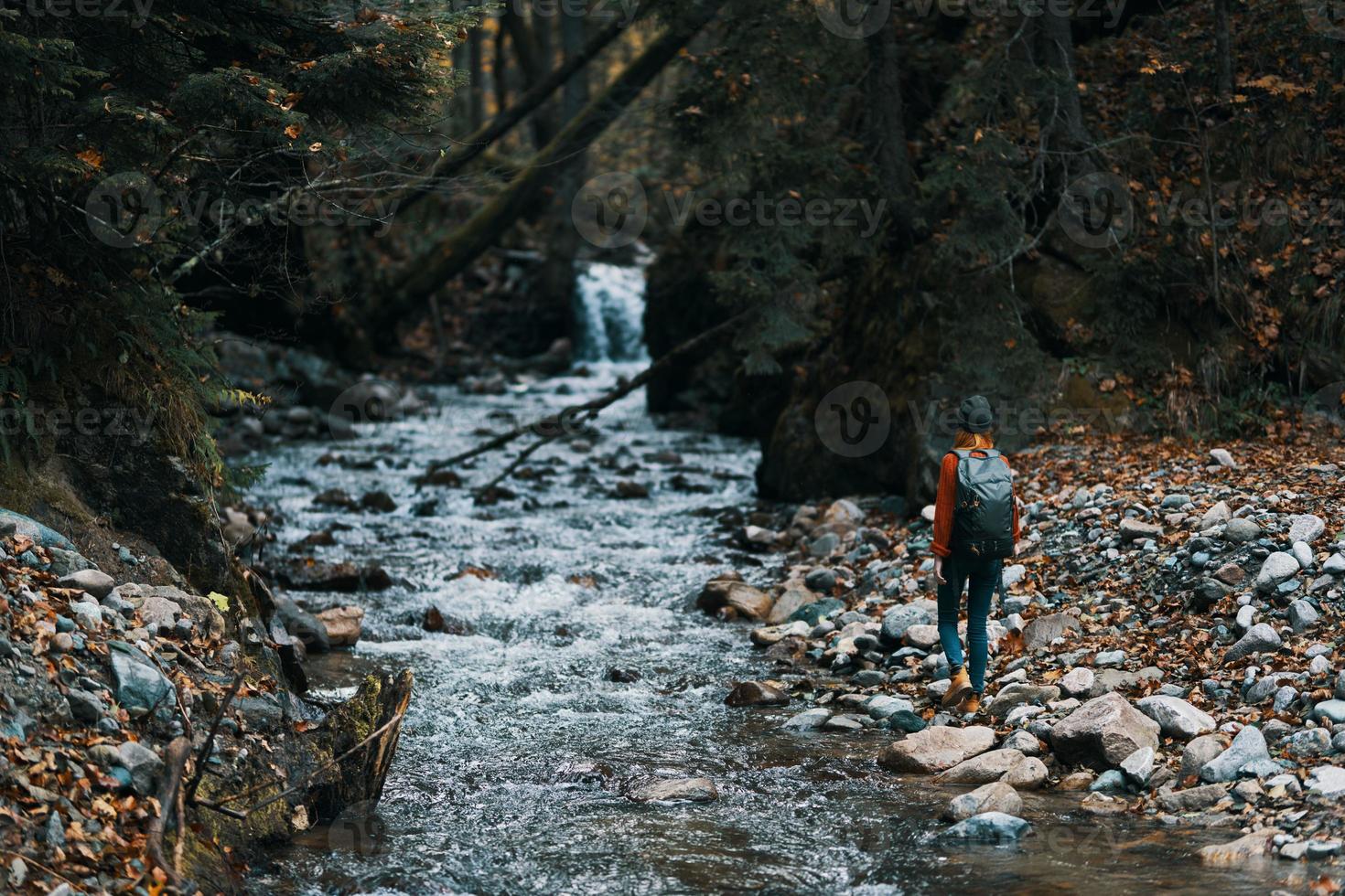 woman in the mountains near the river with a backpack on her back and a forest in the background photo