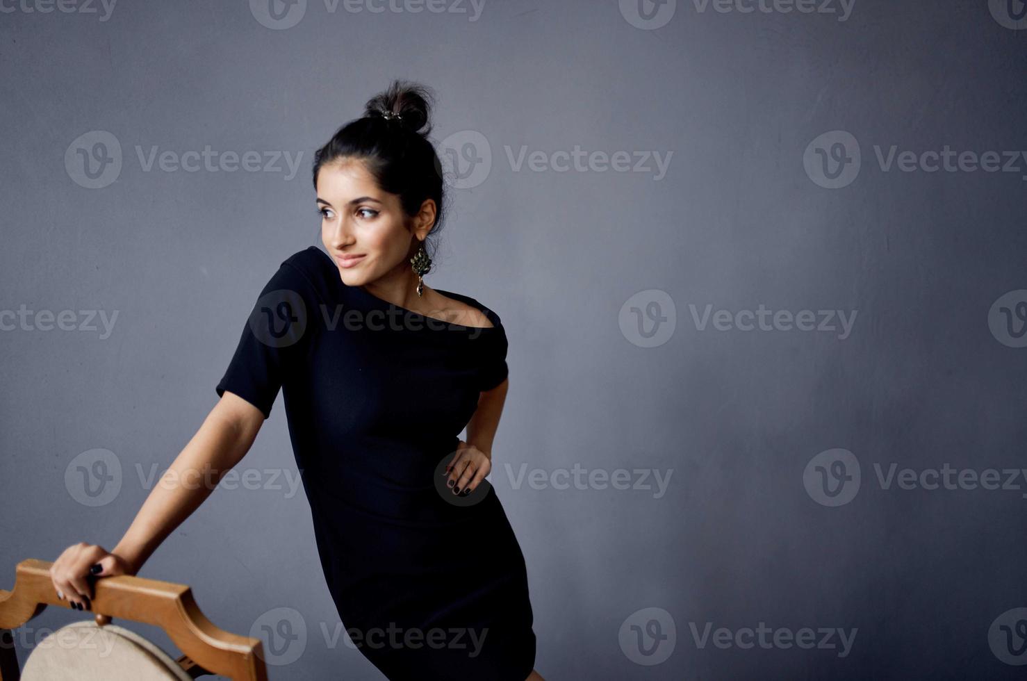 hermosa mujer pendientes joyería posando cerca el silla negro vestir estilo de vida estudio foto