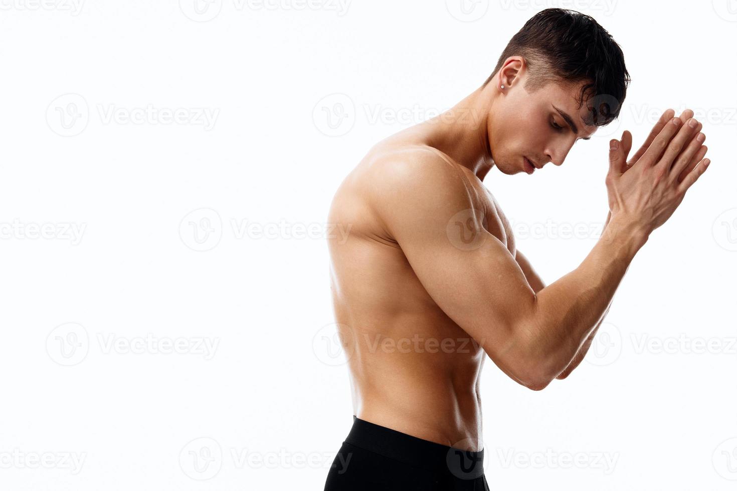 man athlete joined hands near the face on a light background side view photo