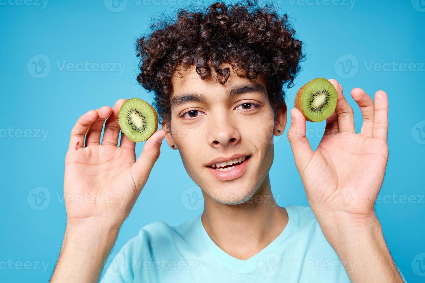 Cheerful guy blue t-shirts kiwi in the hands of vegetarianism fruits photo