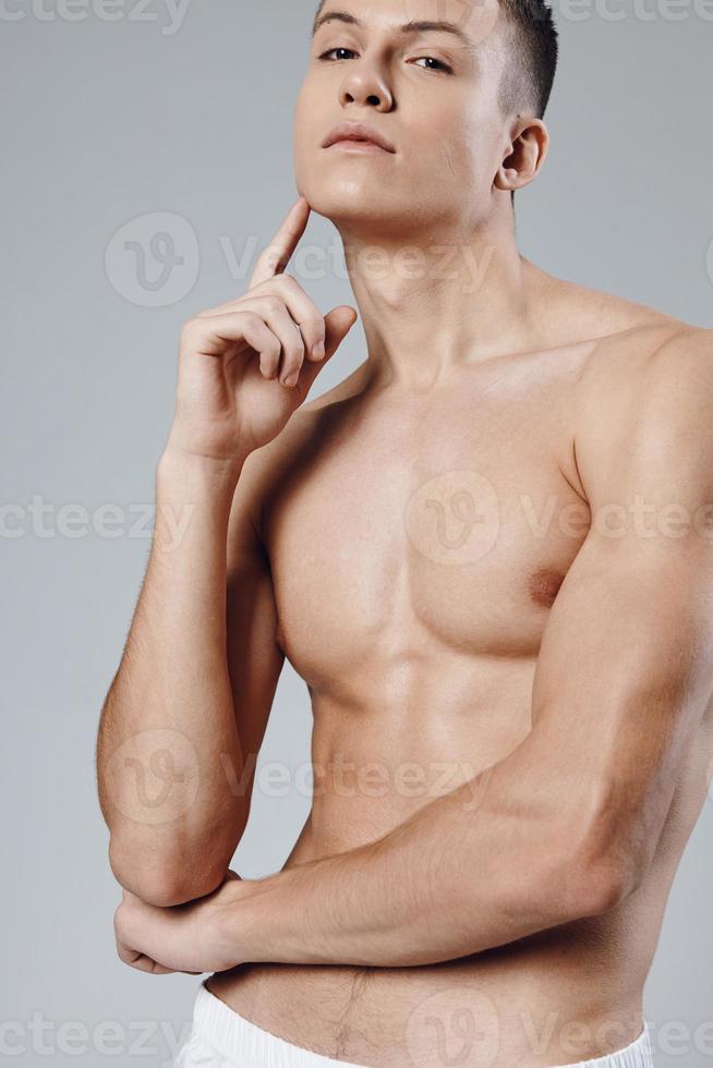 guy with a pumped up press holds a finger near the face on a gray background close-up portrait photo