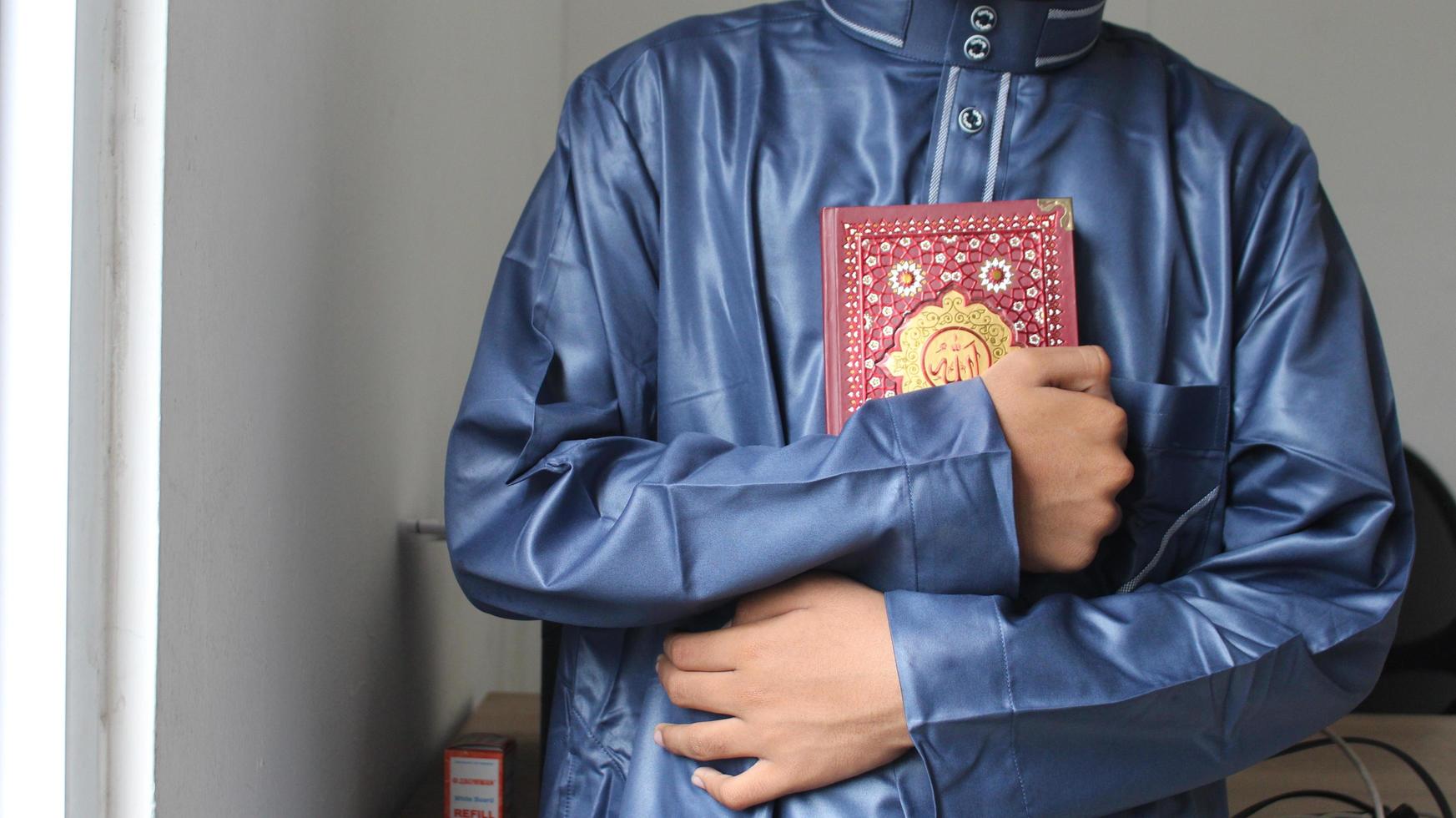 un joven musulmán hombre es participación el Corán a su pecho. foto